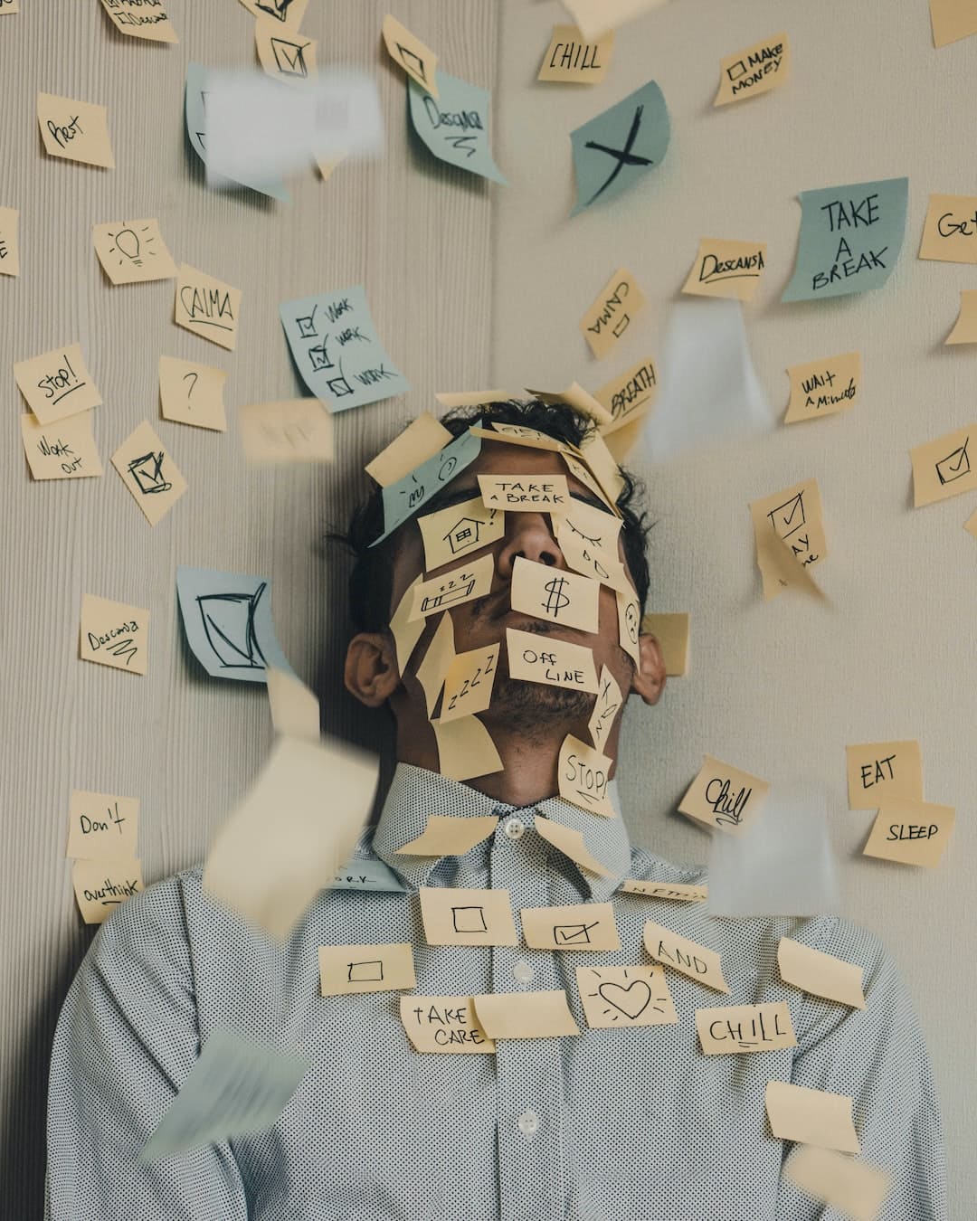 a boy standing alongside wall corner with sticky notes on face and walls