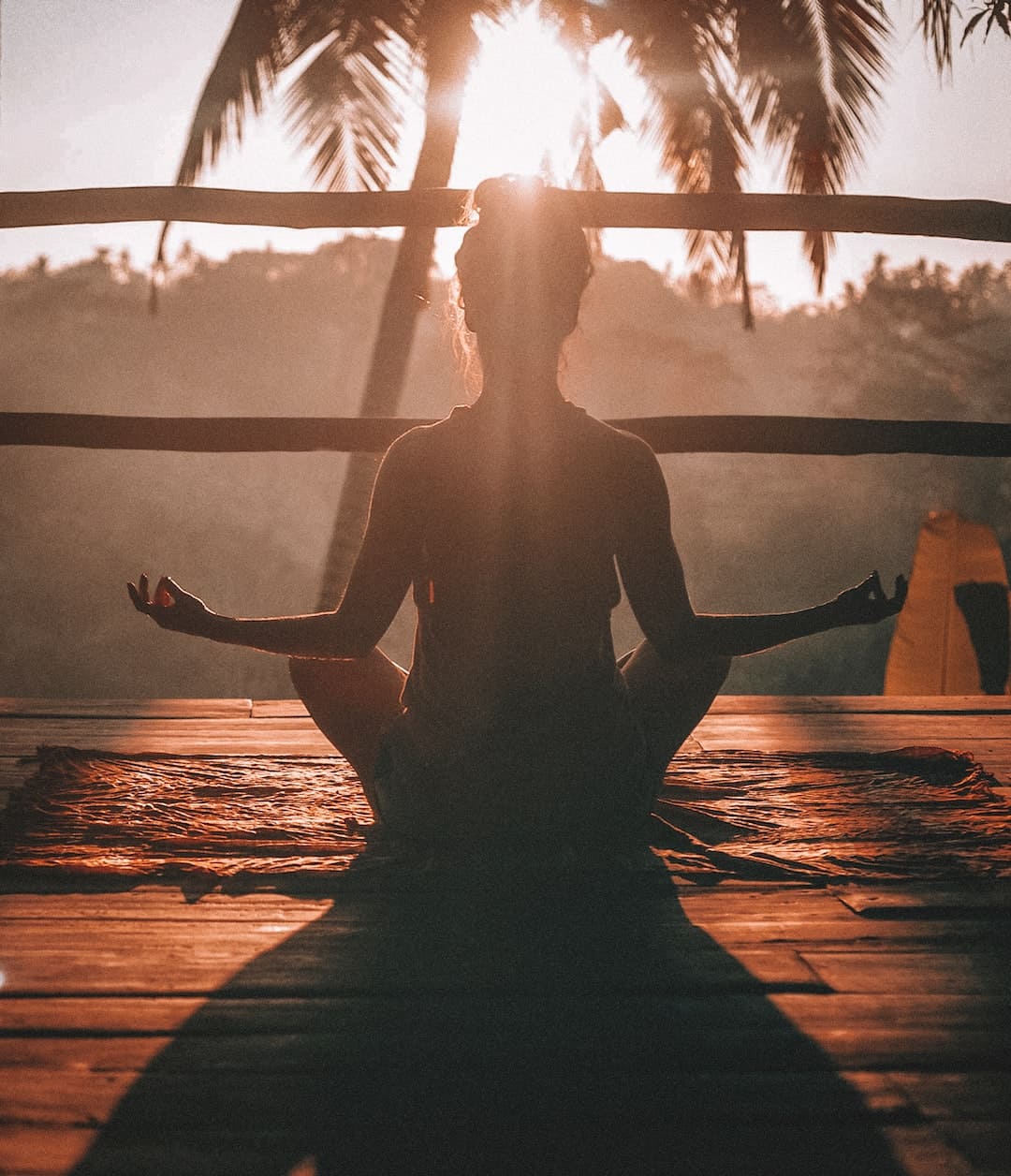 a lady in yoga pose while sun rises